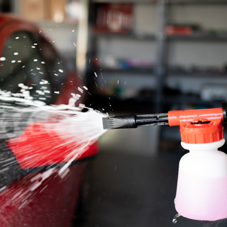 Foam solution being sprayed onto a red vehicle, illustrating AutoBrite Super Cherry Presoak use